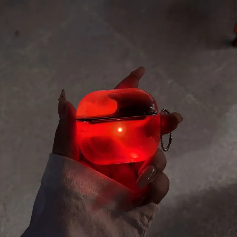 Crimson Red LumiCases AirPods cover glowing deep red in the dark, held in a hand with its keychain