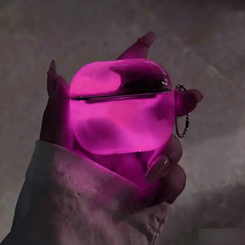 Cotton Candy Pink LumiCases AirPods cover glowing hot pink in the dark, held in a hand with its keychain
